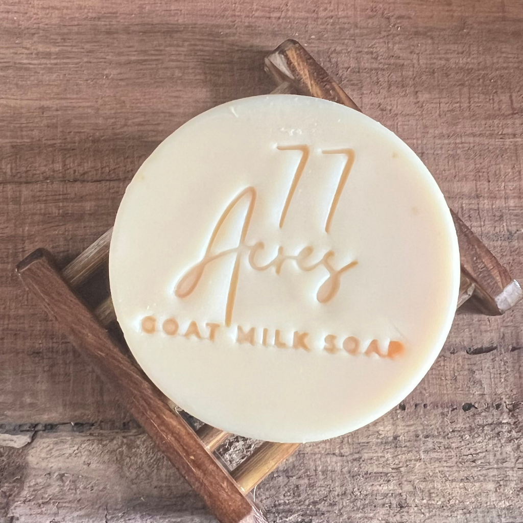 Goat milk soap with '77 Acres' branding on a wooden background